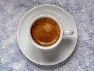 Cup of coffee  on a white textured surface.