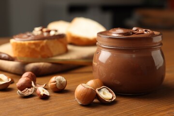 Glass jar with tasty chocolate hazelnut spread and nuts on wooden table. Space for text