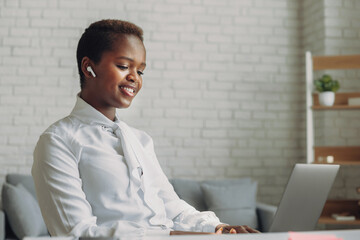 Attractive african young confident businesswoman sitting at the office table working on laptop computer. Concept of trading and financial success. Information