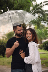 Young couple with umbrella enjoying time together under rain on city street