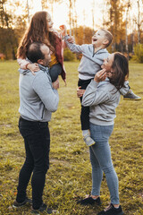 Happy caucasian parents with two children walking in city park, enjoying leisure time. Parent, child. Mother nature. Happy family. Outdoor lifestyle. Autumn