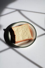 Homemade slide bread  on white plate under morning sunlight. Breakfast bread and coffee.