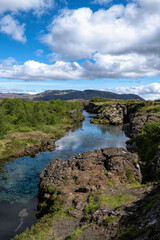 Clouds reflected in glacial water filling a fissure between tectonic plates in Thingvellir National Park, Iceland