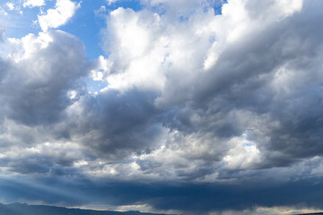 Landscape photograph with dramatic storm clouds over dark hills.