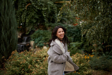 Portrait of pretty asian kazakh brunette woman with charming smile walking along outdoors - 537405202