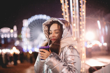 Portrait of happy young woman standing in Christmas market in city at night