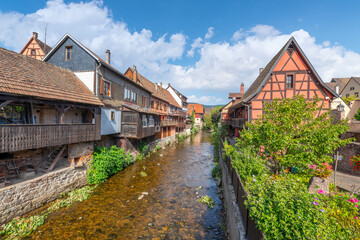 Fototapeta na wymiar Half timbered medieval homes line the Weiss river canal in the historic town center of Kaysersberg, France in the Alsace region. Considered one of the most beautiful villages in France.