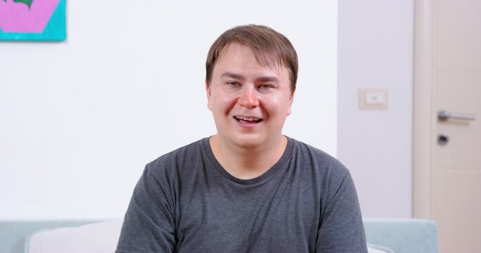 Young man was laughing loudly and barely stopped, so now he is wiping away tears and cannot catch his breath, front view. Portrait of guy, who heard very funny joke.