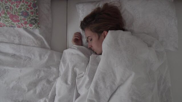 Sleeping caucasian brunette girl in bed, top down slider view