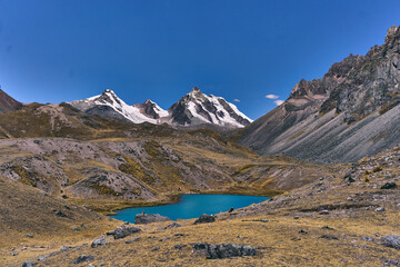 Paisaje de montañas con vegetación y glaciares rodeando laguna color turquesa 