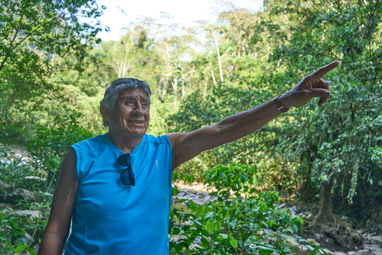 Hombre adulto maduro latino asustado apuntando con el dedo en medio de la selva 