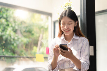 A beautiful young asian woman holding and using mobile phone.