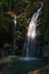 Obraz premium Giant waterfall in the woods with a Little sunlight and shadows 