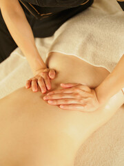 背中をマッサージをするエステティシャン
