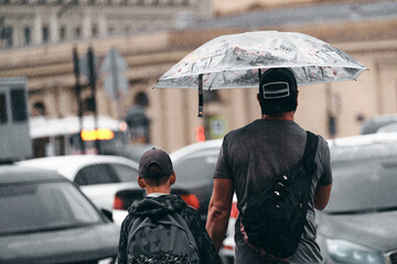 People are waiting for a taxi in the rain outdoors. Family under an umbrella in the downpour waiting for the car. Father with son on the city streets in bad weather