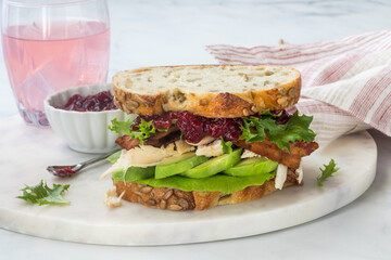 A turkey sandwich with avocado and cranberry sauce, ready for eating.
