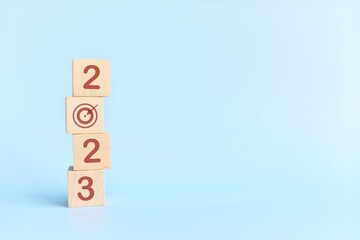 Start New Year 2023 business target goal concept. Human hand stacking wooden blocks with 2023 target icon.