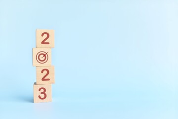 Start New Year 2023 business target goal concept. Human hand stacking wooden blocks with 2023...