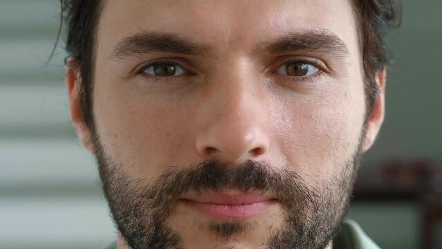 Close-up portrait of a handsome attractive bearded Caucasian young man with powerful brown eyes, staring piercingly at camera. Cropped face portrait of a 30 years old male model with mysterious gaze