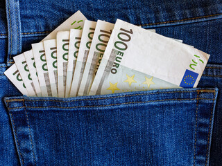 Many 100 euro banknotes in blue jeans pocket top view with copy space. Money, business, finance, saving, banking, wealth, waste concept. Exchange Rates.