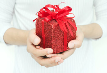 young man's hand holding a red gift box Ready to give to loved ones on Christmas, concepts, couples and important festivals.
