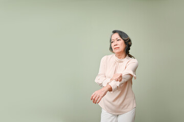 Obraz premium A distressed elderly Asian woman suffering from arm pain, massaging her arm, holding her elbow