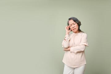 Tired and stressed 60s aged Asian woman touching her forehead, suffering from headache
