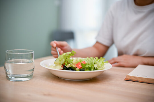 Cropped image, A female eating healthy salad at her dining table. Healthy lifestyle