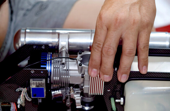 Man's hand holding the engine of an RC plane, he is repairing it.