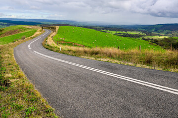 Winding road through Adelaide Hills farms during winter season, South Australia