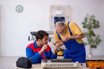 Two male repairmen repairing air-conditioner