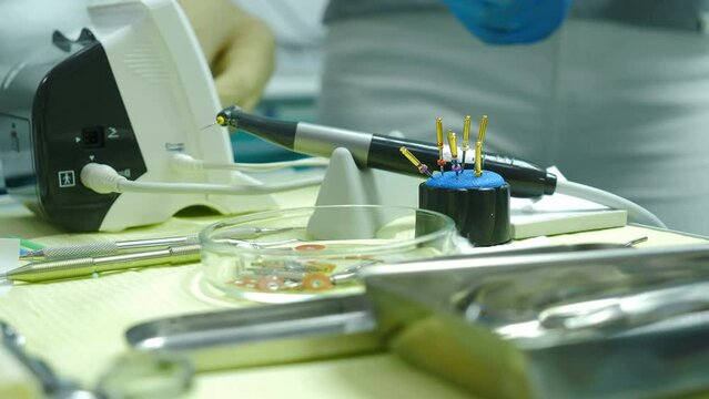 Dental tools on table in clinic with doctor hand in disposable rubber glove choosing taking equipment . Unrecognizable professional dentist MD in office indoors. 4 k video