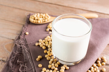 Soy milk in a glass with soybeans on a wooden table organic drink high protein healthy breakfast agricultural produce vegetarian - top view