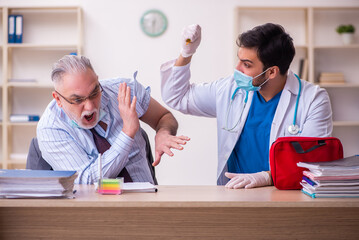 Young male doctor visiting old businessman at workplace