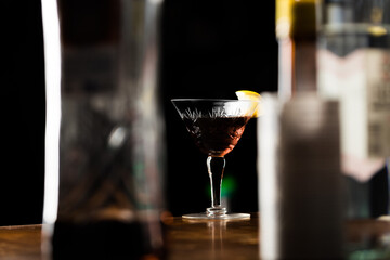 Martinez cocktail a variation of the classic Martini with black background and bottles around