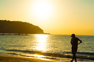 千葉県南房総市の原岡桟橋の夕日と浜辺を散歩する男性