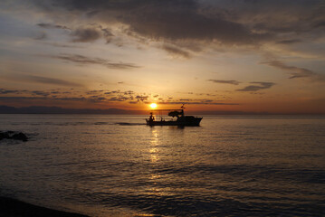 Scenic view on the sea at the sun rise with a boat silhouette