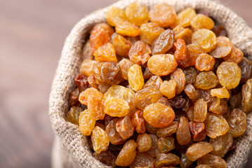 Beautiful composition of raisin in a small bag against black wooden background. Healthy eating, raising concept