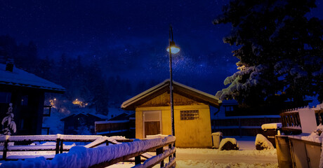 Snow covered wooden chalet in a white winter as The Milky way galaxy with star in the night -Alps,...