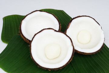 Half cut coconut fruits  to show inside meat  on green banana leaves background. Concept : Food...