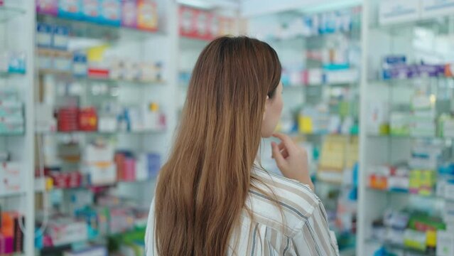 Back view of a woman customer standing and looking products medicines or supplements in the pharmacy
