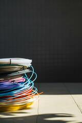 Close-up of plastic bright wires for a 3D printer lying indoors on a white table on a gray background with beautiful shadows. The concept of children's entertainment and creativity.