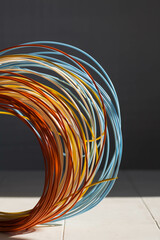 Close-up of plastic bright wires for a 3D printer lying indoors on a white table on a gray...