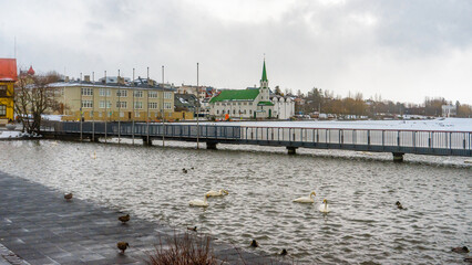 Tjornin Viewpoint lake and buildings next to the Reykjavik City Hall during winter cloudy day in...