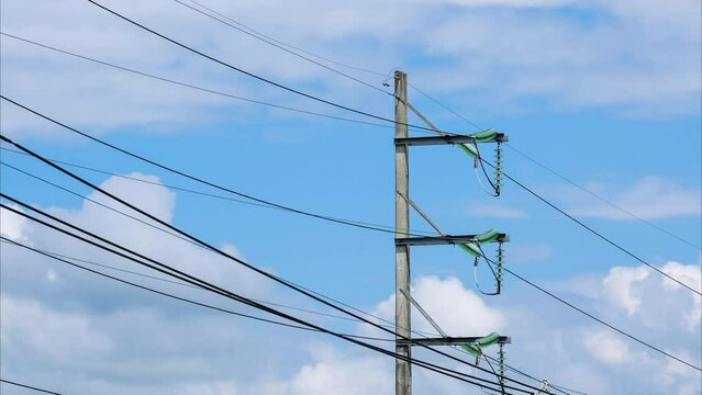 Electric poles and wires in the blue sky with clouds in the countryside.