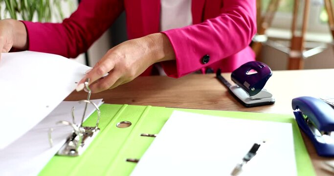 Business woman is punching documents on table in office
