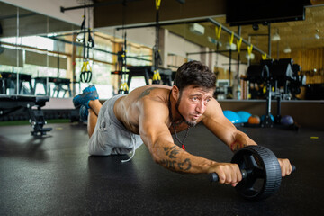 Man doing abs using a roller in the gym