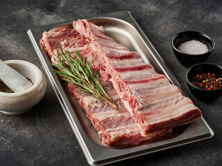 Raw pork ribs with spices, salt, pepper and rosemary. Fresh pork. Pig ribs.