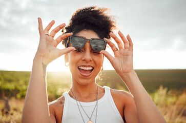 Black woman smile, wink and happy on summer countryside nature holiday at sunset. Girl with fashion sunglasses, laugh with happiness and peace on relax travel vacation trip at South Africa wine farm
