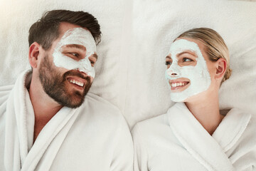 Love, face mask and skincare couple relax, body care and in gowns on spa vacation celebrate anniversary, honeymoon or relationship. Man and woman on holiday smile together, on retreat and bonding.